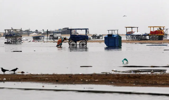 An Indian woman pushes a cart on the waterlogged Marina Beach after heavy rainfall in Chennai, India, Friday, November 13, 2015. Heavy rains lashed Chennai and other parts of Tamil Nadu state Friday, throwing life out of gear and disrupting train and flight schedules even as dozens were killed in rain related incidents, according to news reports. The Indian Meteorological Department has warned of more rains over the weekend. (Photo by Arun Sankar K./AP Photo)