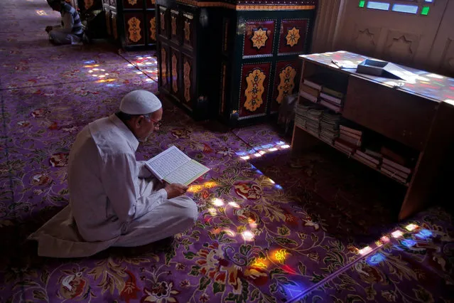 A Muslim man reads the Koran at the shrine of Sheikh Abdul Qadir Jeelani, a Sufi saint, during the holy month of Ramadan in Srinagar May 21, 2018. (Photo by Danish Ismail/Reuters)