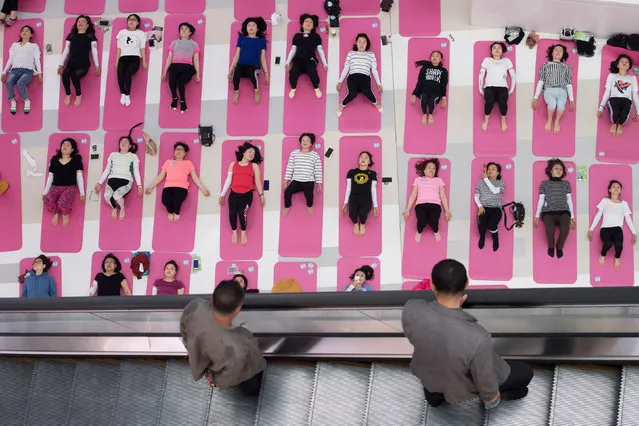 Men look at women attending a yoga session a day ahead of Earth Day, inside a shopping mall in Taiyuan, Shanxi province, China April 21, 2018. (Photo by Reuters/China Stringer Network)