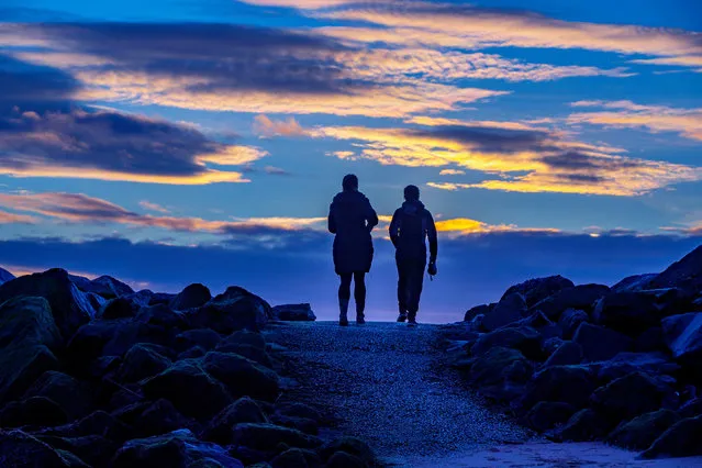 Two women walk their dogs at sunrise on New Brighton beach in Wirral, United Kingdom on January 3, 2021. (Photo by Peter Byrne/PA Images via Getty Images)