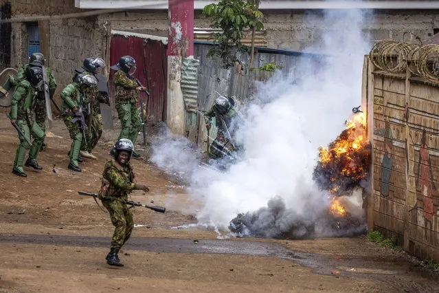 Kenyan riot police react as a tear gas grenade they threw explodes next to them, during clashes with rock-throwing opposition protesters in the Kibera slum of the capital Nairobi, Kenya Tuesday, May 2, 2023. The fresh round of demonstrations called by opposition leader Raila Odinga demanded action to tackle the cost of living and reforms to the electoral commission that oversaw last year's election that was won by President William Ruto. (Photo by Ben Curtis/AP Photo)