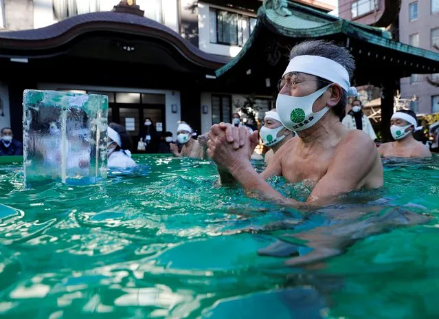 Participants wearing protective face masks amid the coronavirus disease (COVID-19) outbreak, pray as they take an ice-cold bath during a ceremony to purify their souls and to wish for overcoming the pandemic at the Teppozu Inari shrine in Tokyo, Japan, January 10, 2021. (Photo by Kim Kyung-Hoon/Reuters)