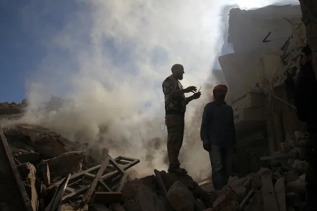 Smoke rises while men inspect damaged buildings after an airstrike on the rebel-held town of Darat Izza, province of Aleppo, Syria November 5, 2016. (Photo by Ammar Abdullah/Reuters)