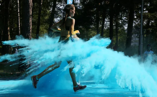 A woman is sprinkled with color powder during a color festival in Jurmala, Latvia, August 16, 2020. (Photo by Edijs Palens/Xinhua News Agency via Getty Images)