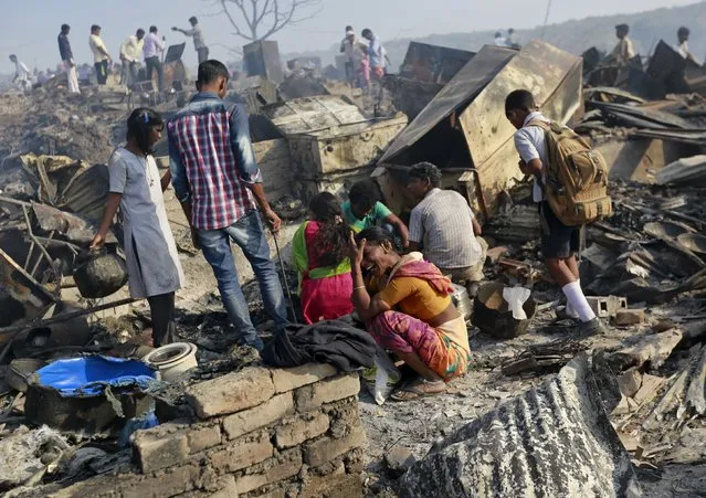 A woman cries as she sits on debris from her gutted hut after a fire occurred in a slum area in Mumbai, India, December 7, 2015. (Photo by Danish Siddiqui/Reuters)