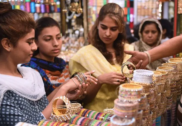 Pakistani women buy bangles at a shop ahead of the Eid al-Fitr holiday which marks the end of the holy month of Ramadan, in Karachi on June 13, 2018. Muslims around the world are preparing to celebrate the Eid al-Fitr holiday, which marks the end of the fasting month of Ramadan. (Photo by Asif Hassan/AFP Photo)