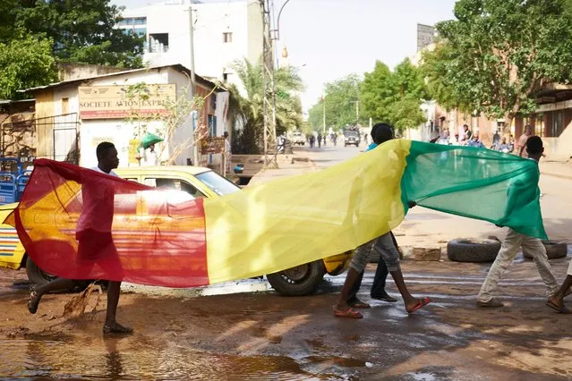 Civilians wave the Malian national flag as they protest against the lack of transparency of the presidential election's campaign, on June 2, 2018 in Bamako. At least a dozen people were wounded on June 2, 2018 in Bamako during a “peaceful march” called by the opposition and banned by the government. The demonstration gathered several hundred people, two months ahead of the presidential election, according to a correspondent of the AFP. (Photo by Michele Cattani/AFP Photo)