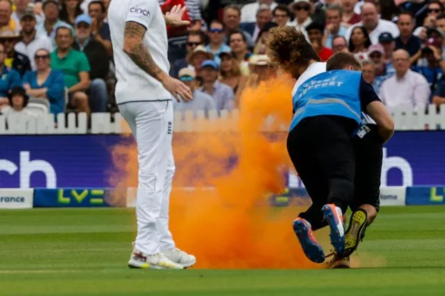 A Just Stop Oil protester is stopped by a member of security after entering the pitch to throw orange powder during the day one of the second Ashes cricket Test match between England and Australia at Lord's cricket ground in London, on June 28, 2023. (Photo by Ian Kington/AFP Photo)
