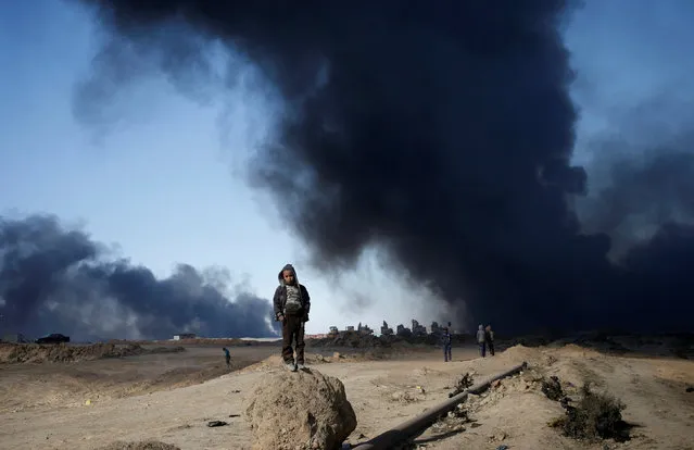 A boy stands in front of oilfields burned by Islamic State fighters in Qayyara, south of Mosul, Iraq November 23, 2016. (Photo by Goran Tomasevic/Reuters)