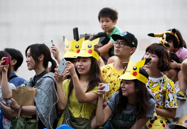 People take photographs of performers dressed as Pikachu, a character from Pokemon series game titles, marching during the Pikachu Outbreak event hosted by The Pokemon Co. on August 10, 2018 in Yokohama, Kanagawa, Japan. (Photo by Tomohiro Ohsumi/Getty Images)