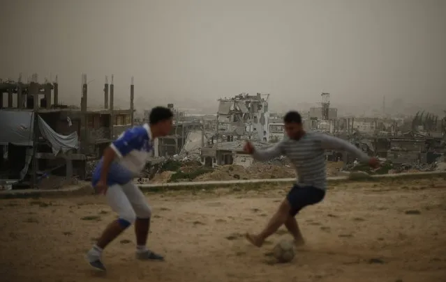 Palestinians play soccer in front of ruined houses, which witnesses said were destroyed by Israeli shelling during a 50-day war last summer, on a stormy day in the east of Gaza City February 10, 2015. (Photo by Mohammed Salem/Reuters)