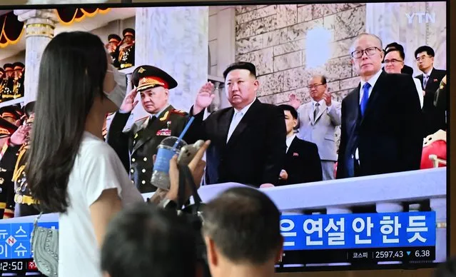 A woman walks past a television screen showing a news broadcast with an image of North Korean leader Kim Jong Un attending a military parade held in Pyongyang to mark the 70th anniversary of the Korean War armistice, at a railway station in Seoul on July 28, 2023. Kim Jong Un oversaw a North Korean military parade featuring new drones and Pyongyang's nuclear-capable intercontinental ballistic missiles, as his defence chief warned the United States that nuclear war was coming, state media reported on July 28. (Photo by Jung Yeon-je/AFP Photo)