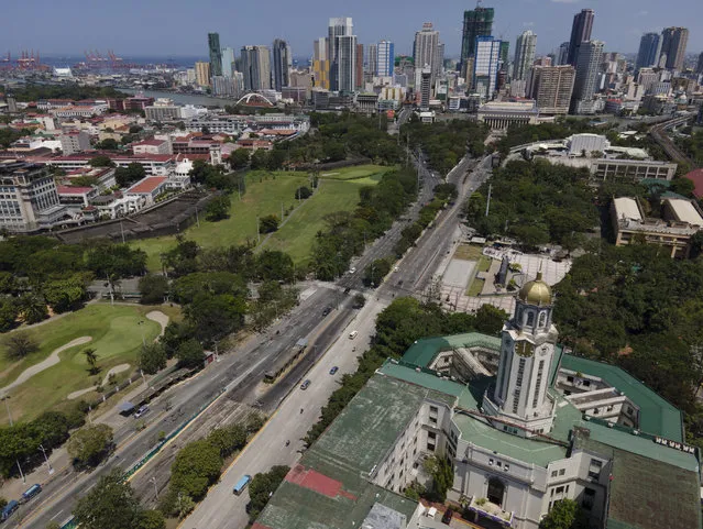 Manila city hall is seen beside an almost empty road as the government implements a strict lockdown to prevent the spread of the coronavirus on Good Friday, April 2, 2021 in Manila, Philippines. Filipinos marked Jesus Christ's crucifixion Friday in one of the most solemn holidays in Asia's largest Catholic nation which combined with a weeklong coronavirus lockdown to empty Manila's streets of crowds and heavy traffic jams. Major highways and roads were eerily quiet on Good Friday and churches were deserted too after religious gatherings were prohibited in metropolitan Manila and four outlying provinces. (Photo by Aaron Favila/AP Photo)
