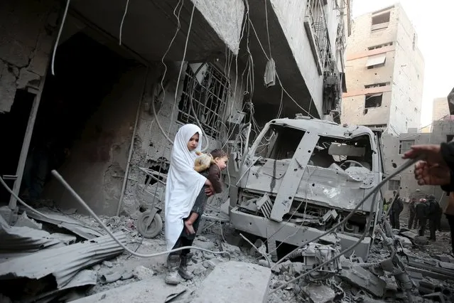 A girl carrying a baby inspects damage in a site hit by what activists said were airstrikes carried out by the Russian air force in the town of Douma, eastern Ghouta in Damascus, Syria January 10, 2016. (Photo by Bassam Khabieh/Reuters)