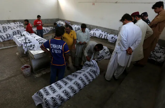 Men gather at hospital morgue to identify their relatives who were killed after a fire had erupted in a hotel early morning in Karachi, Pakistan, December 5, 2016. (Photo by Akhtar Soomro/Reuters)