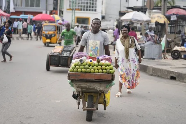 A man wheels a barrow with lemons on the streets of Lagos, Nigeria, Tuesday, September 5, 2023. (Photo by Sunday Alamba/AP Photo)