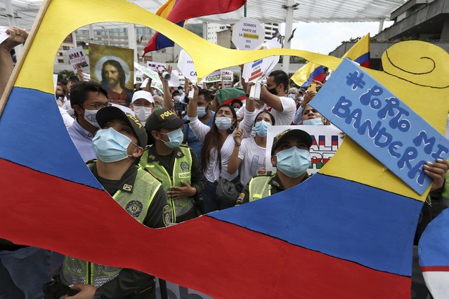 Police and civilians attend a silent march to support the unblocking of the city's main entrance and exit roads that have been blocked by anti-government protests in Cali, Colombia, Tuesday, May 25, 2021. Colombians have taken to the streets for weeks across the country after the government proposed tax increases on public services, fuel, wages, and pensions. (Photo by Andres Gonzalez/AP Photo)