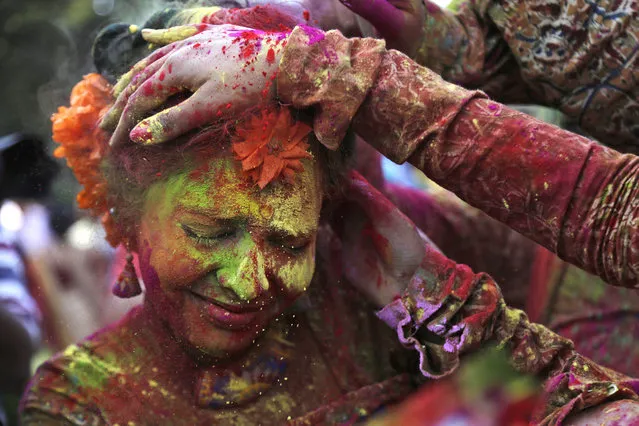 FILE - In this Thursday, March 5, 2015 file photo, people smear colored powder on the face of a girl as they celebrate Holi in Kolkata, India. (AP Photo/ Bikas Das, File)