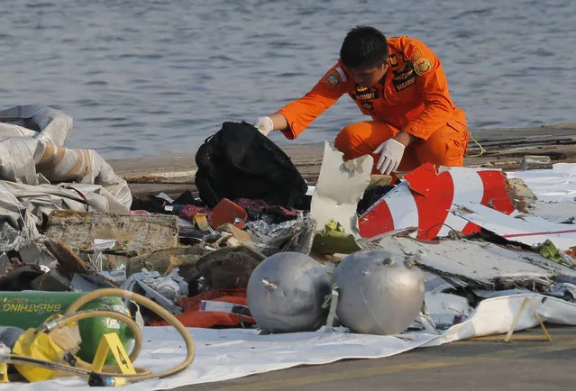 A member of Indonesian Search and Rescue Agency (BASARNAS) inspects debris believed to be from Lion Air passenger jet that crashed off Java Island at Tanjung Priok Port in Jakarta, Indonesia Monday, October 29, 2018. A Lion Air flight crashed into the sea just minutes after taking off from Indonesia's capital on Monday in a blow to the country's aviation safety record after the lifting of bans on its airlines by the European Union and U.S. (Photo by Tatan Syuflana/AP Photo)