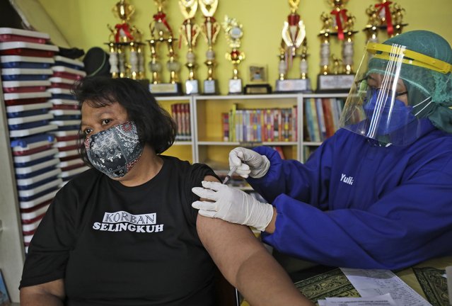 A woman receives a shot of the AstraZeneca vaccine during a mass coronavirus vaccination held at a children's library in Jakarta, Indonesia, Tuesday, June 8, 2021. The world's fourth-most populous country, with about 275 million people, has reported more coronavirus cases than any other Southeast Asian country. (Photo by Dita Alangkara/AP Photo)