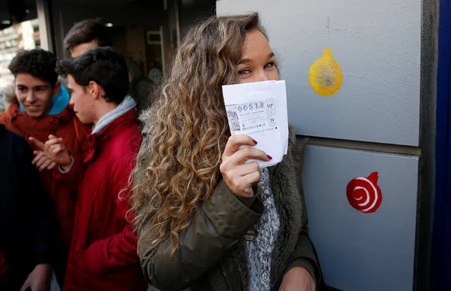 Sergia holds up a photocopy of the winning ticket number she bought as she joins others celebrating outside the kiosk where the winning number was sold in Spain's Christmas Lottery “El Gordo” (The Fat One) in Madrid, Spain, December 22, 2016. (Photo by Juan Medina/Reuters)
