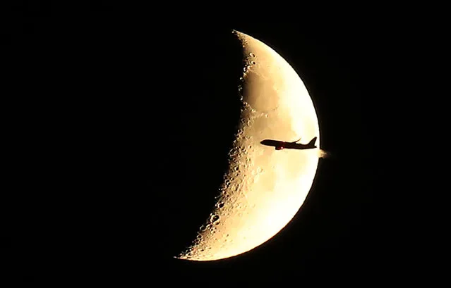A plane flies past a crescent moon in Moscow, Russia on June 17, 2021. (Photo by Sergei Savostyanov/TASS)