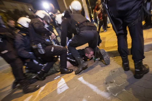 In this Wednesday, November 14, 2018 photo, a demonstrator is detained by national police, during a protest at the entrance of a hotel where the newcomer to Spanish politics, the far-right Vox party is holding a rally in Murcia, Spain. (Photo by Emilio Morenatti/AP Photo)
