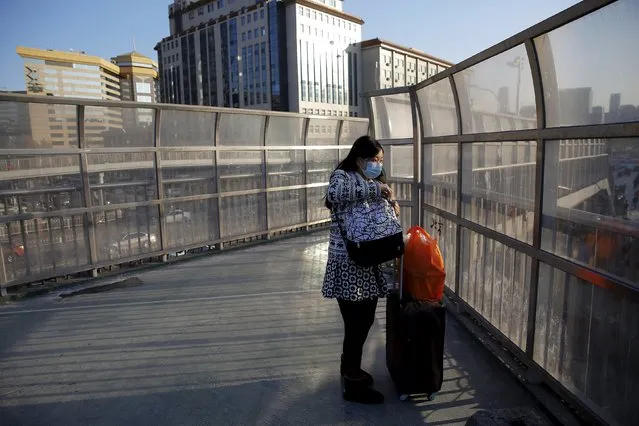 A passenger looks at the Beijing Railway Station from an overpass as migration for the annual Spring Festival begins in central Beijing, January 24, 2016. (Photo by Damir Sagolj/Reuters)