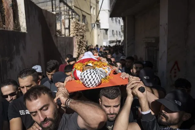 Palestinians carry the body of Ibrahim Zayed, 29, during his funeral in the West Bank refugee camp of Qalandia, south of Ramallah, Friday, November 3, 2023. Zayed was killed during an Israeli army raid in Qalandia early morning, Palestinian Health Ministry said. (Photo by Nasser Nasser/AP Photo)