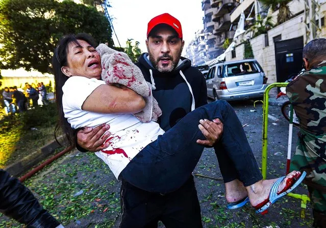 A man carries an injured worker after two explosions near the Iranian Embassy in Beirut, Lebanon, on November 19, 2013. (Photo by Hussein Malla/Associated Press)