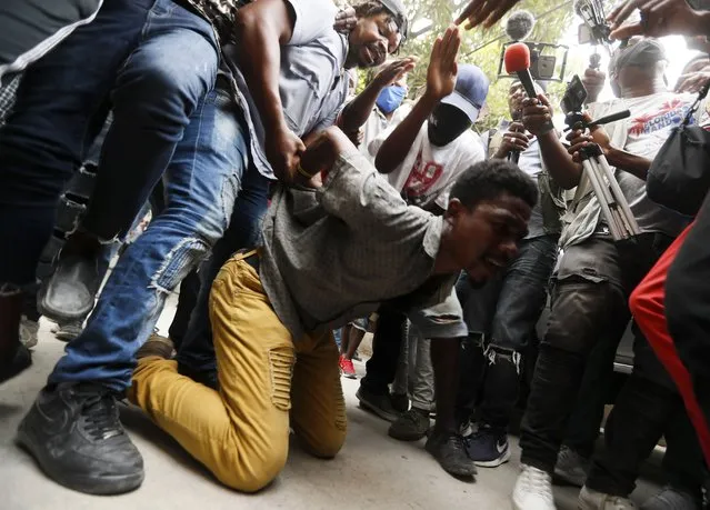 Supporters of former Senator Steven Benoit perform a mock execution for the adversaries of the senator, outside the courthouse as he departs after being called in for questioning in Port-au-Prince, Monday, July 12, 2021. (Photo by Fernando Llano/AP Photo)