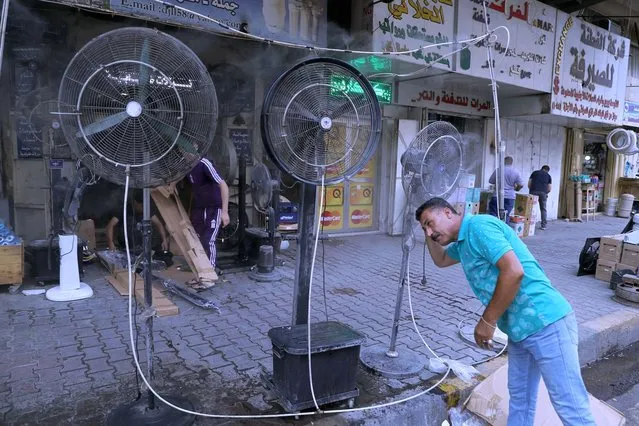 A man cools off from the summer heat under an open air shower to beat the heat in Baghdad, Iraq, Thursday, July 1, 2021. Iraq's government declared Thursday an official holiday in Baghdad due to a scorching heatwave. (Photo by Khalid Mohammed/AP Photo)