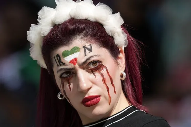 A woman stands on the tribune with her face painted in memory of Mahsa Amini, a woman who died while in police custody in Iran at the age of 22, prior to the World Cup group B soccer match between Wales and Iran, at the Ahmad Bin Ali Stadium in Al Rayyan , Qatar, Friday, November 25, 2022. (Photo by Frank Augstein/AP Photo)