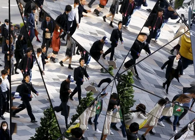 People are reflected in mirrors as they walk in a busy shopping district in Tokyo, Japan, December 25, 2015. (Photo by Thomas Peter/Reuters)