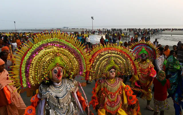 Indian folk dancers perform the “Chhou” dance for Hindu devotees taking a holy bath and performing rituals at the Gangasagar Island, around 150 kms south of Kolkata on January 12, 2017. More than 700,000 Hindu pilgrims and sadhus – holy men – are expected to gather at the confluence of the River Ganges and the Bay of Bengal during the Gangasagar Mela to take a 'holy dip' in the ocean on the occasion of Makar Sankranti, a holy day of the Hindu calendar considered to be of great religious significance in Hindu mythology. (Photo by Dibyangshu Sarkar/AFP Photo)