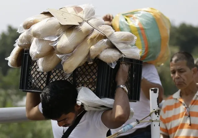 A Venezuelan man carries a crate filled with bread back to his country, in La Parada, on the outskirts of Cucuta, Colombia, on the border with Venezuela, Monday, February 4, 2019. More than a dozen European Union countries endorsed Venezuelan opposition leader Juan Guaido as the county's interim president on Monday, piling the pressure on embattled President Nicolas Maduro to resign and clear the way for a new presidential election. (Photo by Fernando Vergara/AP Photo)