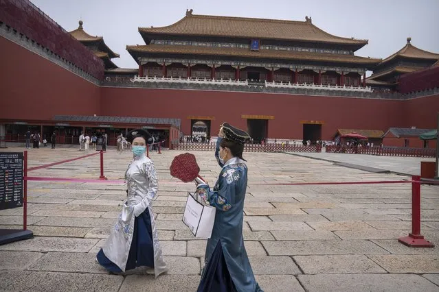 Visitors in historical dress and wearing face masks to protect against COVID-19 walk near the entrance to the Forbidden City in Beijing, Saturday, September 18, 2021. (Photo by Mark Schiefelbein/AP Photo)