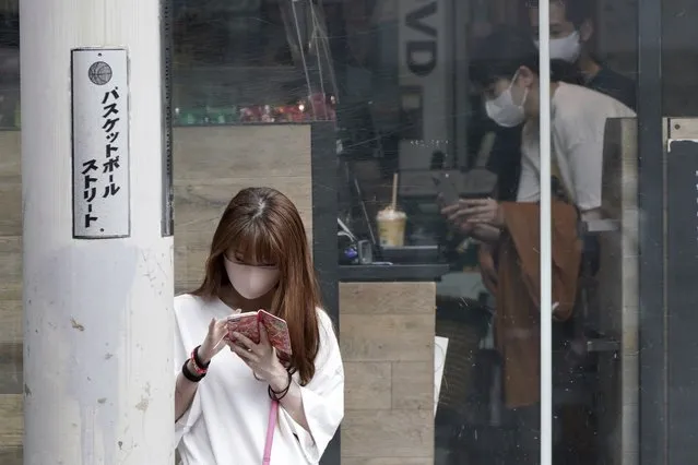 A woman wearing a protective mask to help curb the spread of the coronavirus looks at a mobile phone at Shibuya district Thursday, September 30, 2021, in Tokyo. Fumio Kishida, the man soon to become Japan’s next prime minister, says he believes raising incomes is the only way to get the world’s third-largest economy growing again. Top of Kishida’s to-do list is another big dose of government spending to help Japan recover from the COVID-19 shock. (Photo by Eugene Hoshiko/AP Photo)