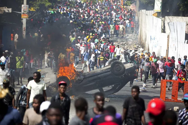 An overturned car burns during a protest demanding the resignation of Haitian President Jovenel Moise in Port-au-Prince, Haiti, Tuesday, February 12, 2019. (Photo by Dieu Nalio Chery/AP Photo)