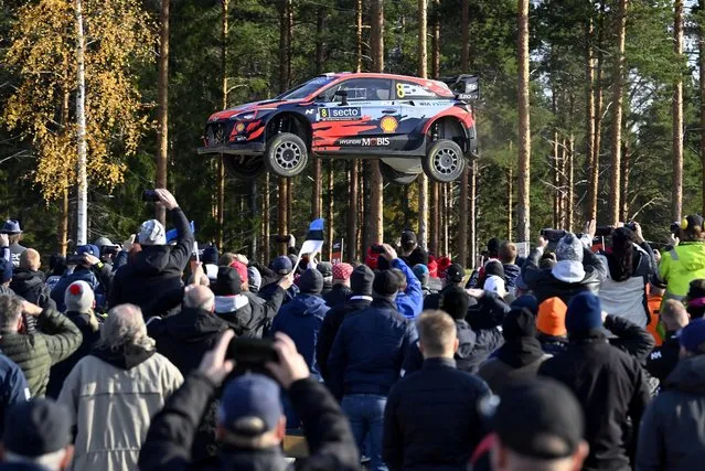 Spectators watch as the Hyundai of Estonian driver Ott Tänak and his Estonian co-driver Martin Järveoja soars through the air during the special stage 19, Ruuhimäki, at the WRC Rally Finland in Laukaa, Finland, on October 3, 2021. (Photo by Jussi Nukari/Lehtikuva via AFP Photo)