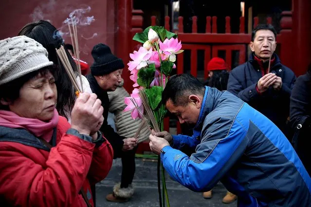 People pray for good fortune as they hold burning incense on the first day of the Chinese Lunar New Year at Yonghegong Lama Temple in Beijing. (Photo by Feng Li/Getty Images)