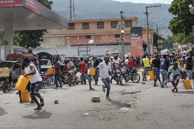 People run for cover as police shoot into the air to disperse a crowd threatening to burn down a gas station because they believed the station was withholding the gas, in Port-au-Prince, Haiti, Saturday, October 23, 2021. (Photo by Matias Delacroix/AP Photo)