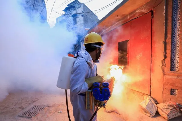 Fire blows from a fogging machine as a worker sprays fumigation vapour to stem the spread of dengue virus along a street in Peshawar, Pakistan, October 18, 2021. (Photo by Fayaz Aziz/Reuters)
