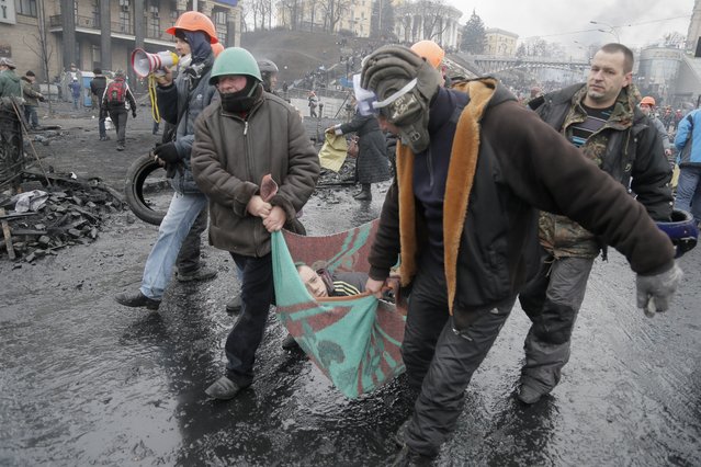 Activists  evacuate a wounded protester during clashes with police in Kiev's Independence Square, the epicenter of the country's current unrest, Kiev, Ukraine, Thursday, February 20, 2014. (Photo by Efrem Lukatsky/AP Photo)