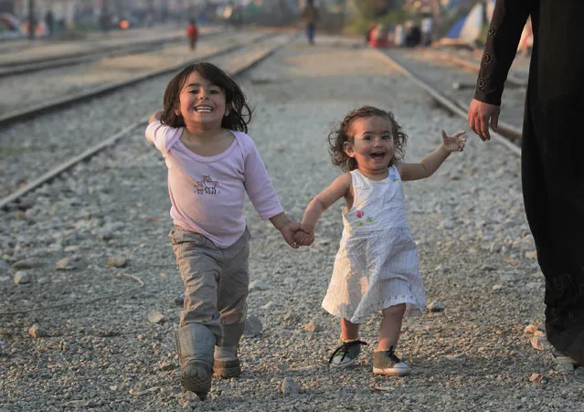 Migrant children walk with their mother on the railway tracks at the northern Greek border point of Idomeni, Greece, Sunday, March 20, 2016. German Chancellor Angela Merkel is urging migrants in the squalid tent city at Idomeni, on the Greek-Macedonian border, to trust Greek authorities and leave for better accommodation as thousands are still staying on site after the closure of Macedonia's border. (Photo by Vadim Ghirda/AP Photo)