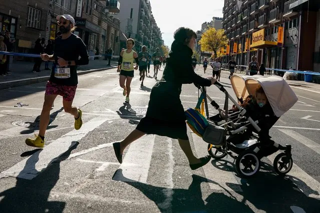 A lady attempts to cross the street as the New York City Marathon participants pass through the borough of Brooklyn in New York, United States on November 7, 2021. (Photo by David Dee Delgado/Reuters)