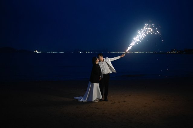 A couple pose for a wedding picture on the beach in Qingdao, China's Shandong province on April 19, 2024. (Photo by Wang Zhao/AFP Photo)