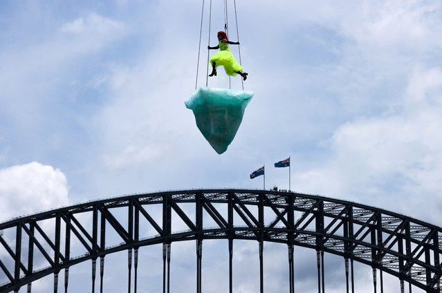 Artist Victoria Hunt performs “Thaw” atop an “iceberg” suspended above Sydney Harbour and in front of the Sydney Harbour Bridge as part of the 2022 Sydney Festival in Sydney on January 14, 2022. (Photo by David Gray/AFP Photo)
