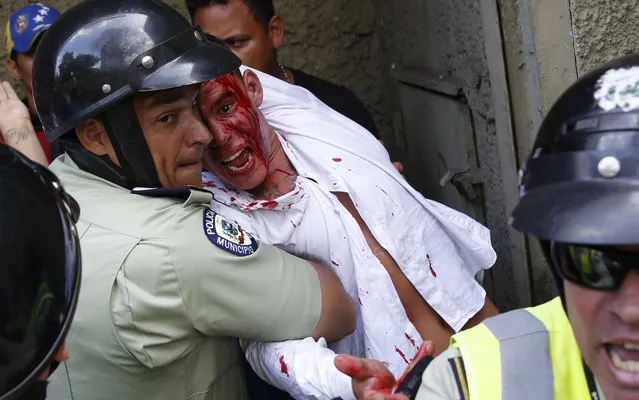 Police protect a man from being hurt by anti-government protesters who accuse him of being a government spy, during an anti-government demonstration in Caracas April 4, 2014. (Photo by Carlos Garcia Rawlins/Reuters)