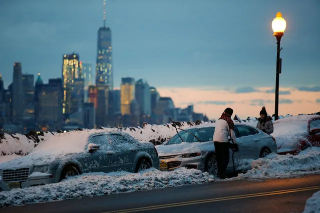 Residents clear their cars and street of snow in Weehawken, New Jersey, as the One World Trade Center and lower Manhattan are seen after a snowstorm in New York, U.S., March 15, 2017. (Photo by Eduardo Munoz/Reuters)